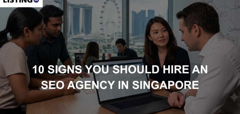Business professionals review SEO analytics on a laptop inside a Singapore office overlooking the Marina Bay skyline.